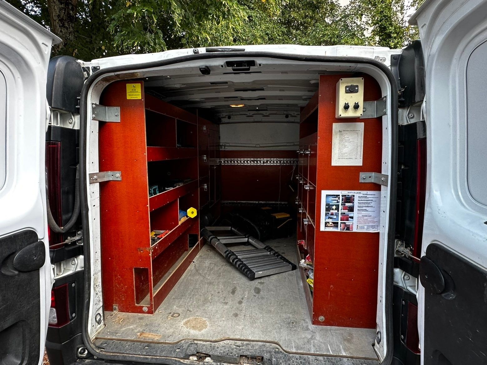 Intérieur du camion aménagé avec étagères, outillage et échelle